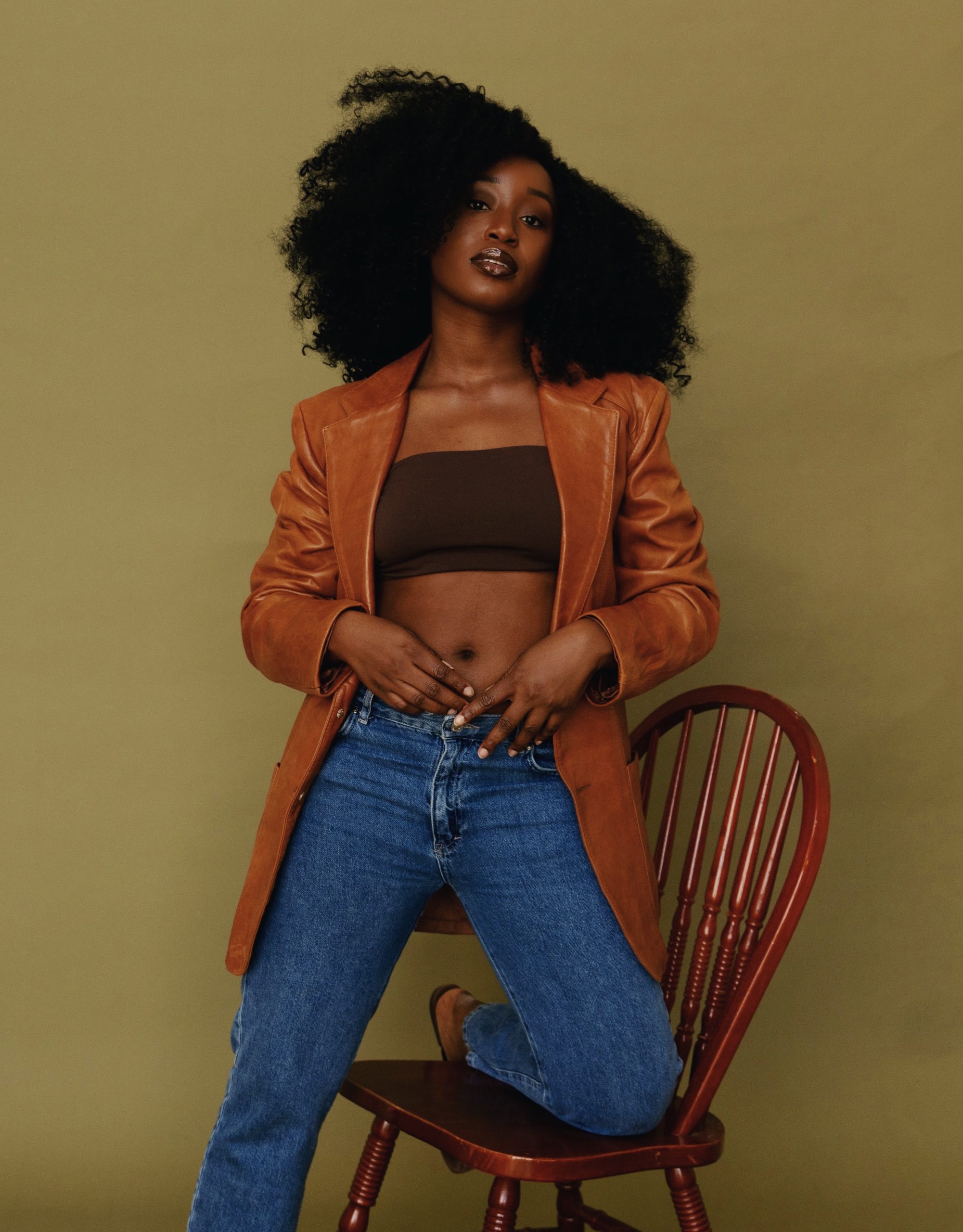 Tumi Adeleye in a brown blazer and jeans with a deep brown brallette